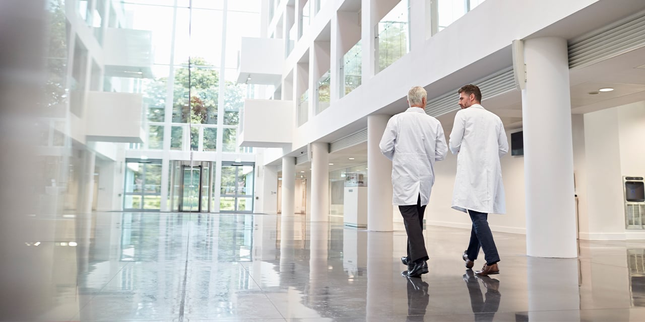 Two medical professionals walking through an office hallway